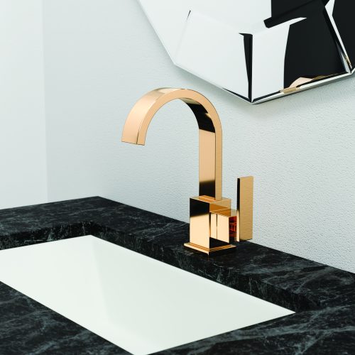 A modern bathroom sink with a black marble countertop features a sleek gold faucet. A geometric mirror is mounted on the white wall behind it.